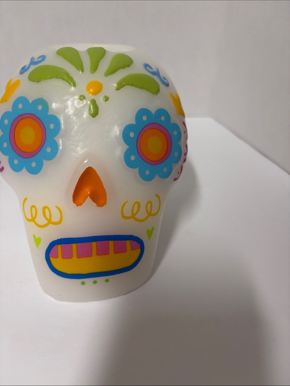 white decorative candle shaped like a sugar skull, adorned with colorful floral